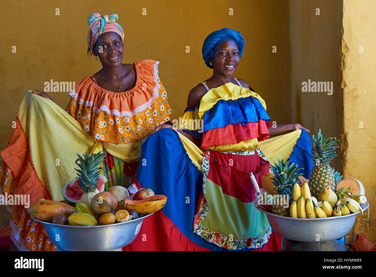 Las mujeres en trajes tradicionales posan para una fotografía, mientras que  la venta de fruta fresca en el centro histórico de la ciudad amurallada de  Cartagena de Indias, en Colombia Fotografía de