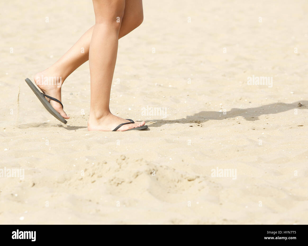 Vista lateral del joven caminando por la playa con chanclas Fotografía de  stock - Alamy