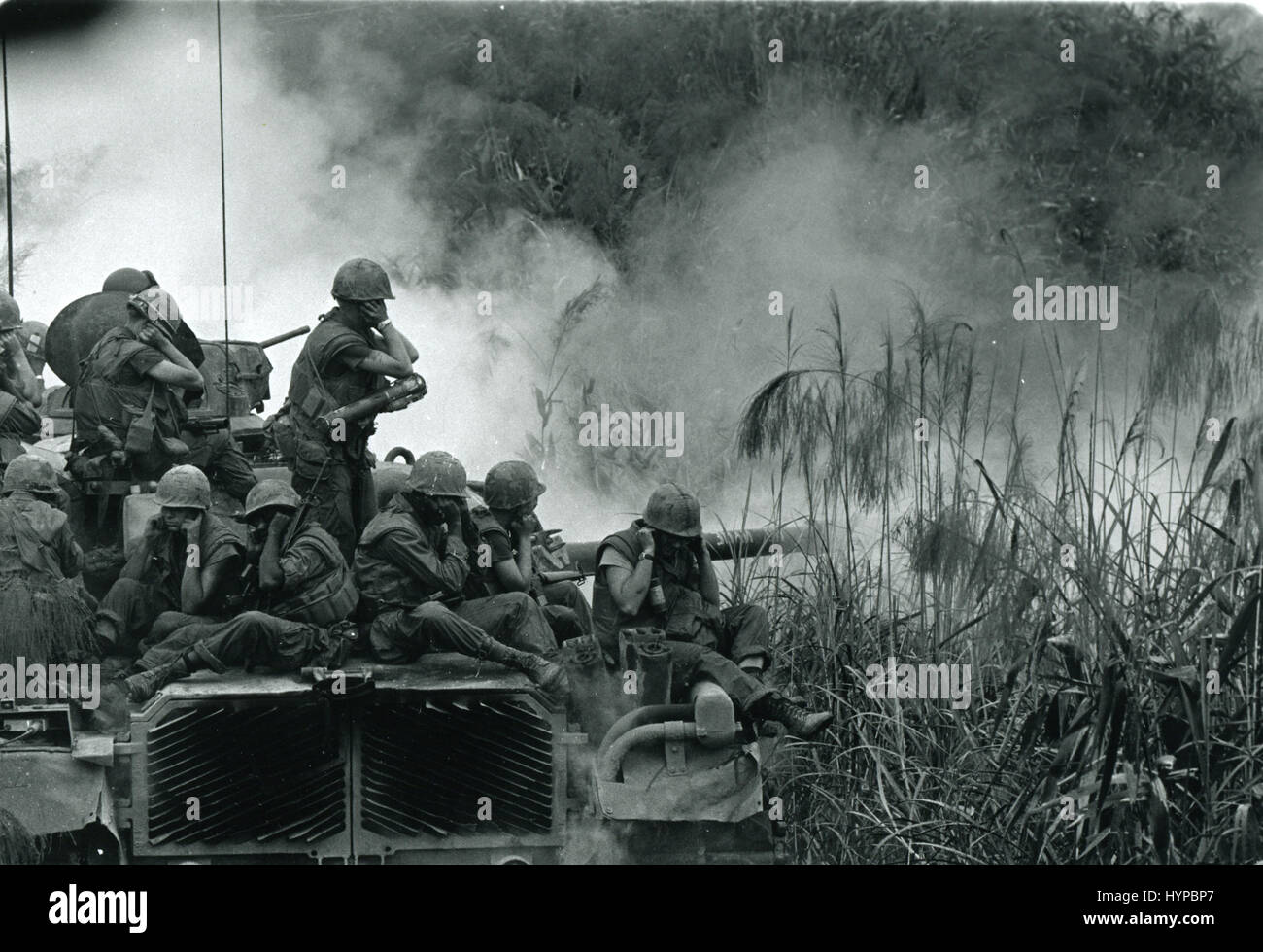 Los marines cabalgando encima de un tanque M-48 cubrir sus oídos como los 90mm pistola fuegos durante un barrido de carretera al suroeste de Phu Bai, 3 de abril de 1968 Foto de stock