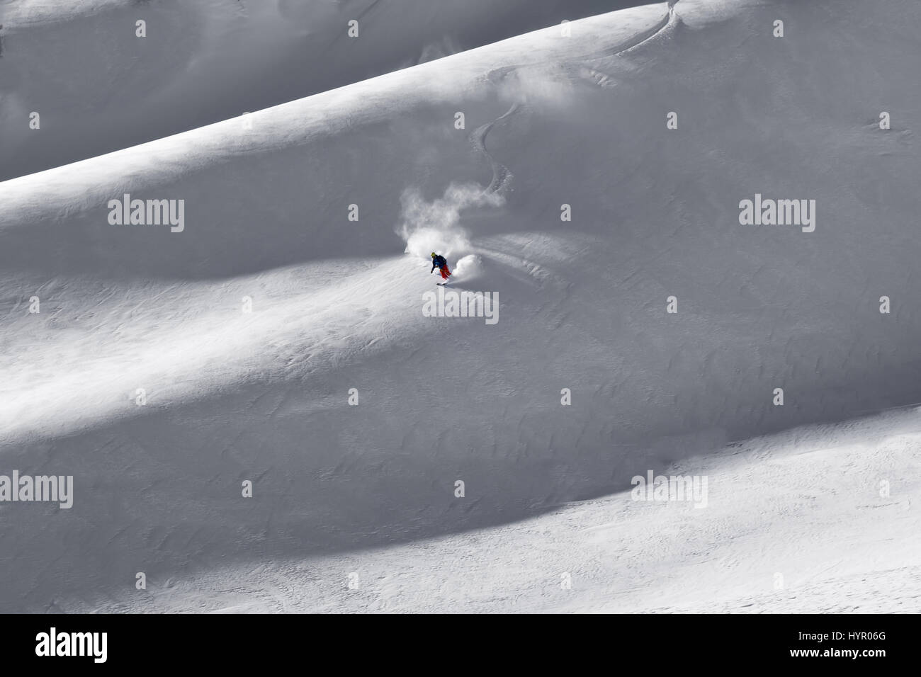 Courmayeur, Italia - 16 de enero de 2017: primeras pistas frescas, presentadas por el único esquiador solitario bajando de la montaña y pulverizando nuevos caído nieve en giros Foto de stock