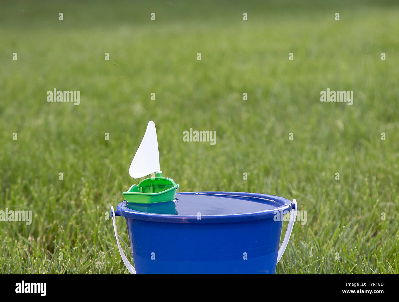 Un juguete de plástico pequeño velero flotando en un cubo de agua. Foto de stock