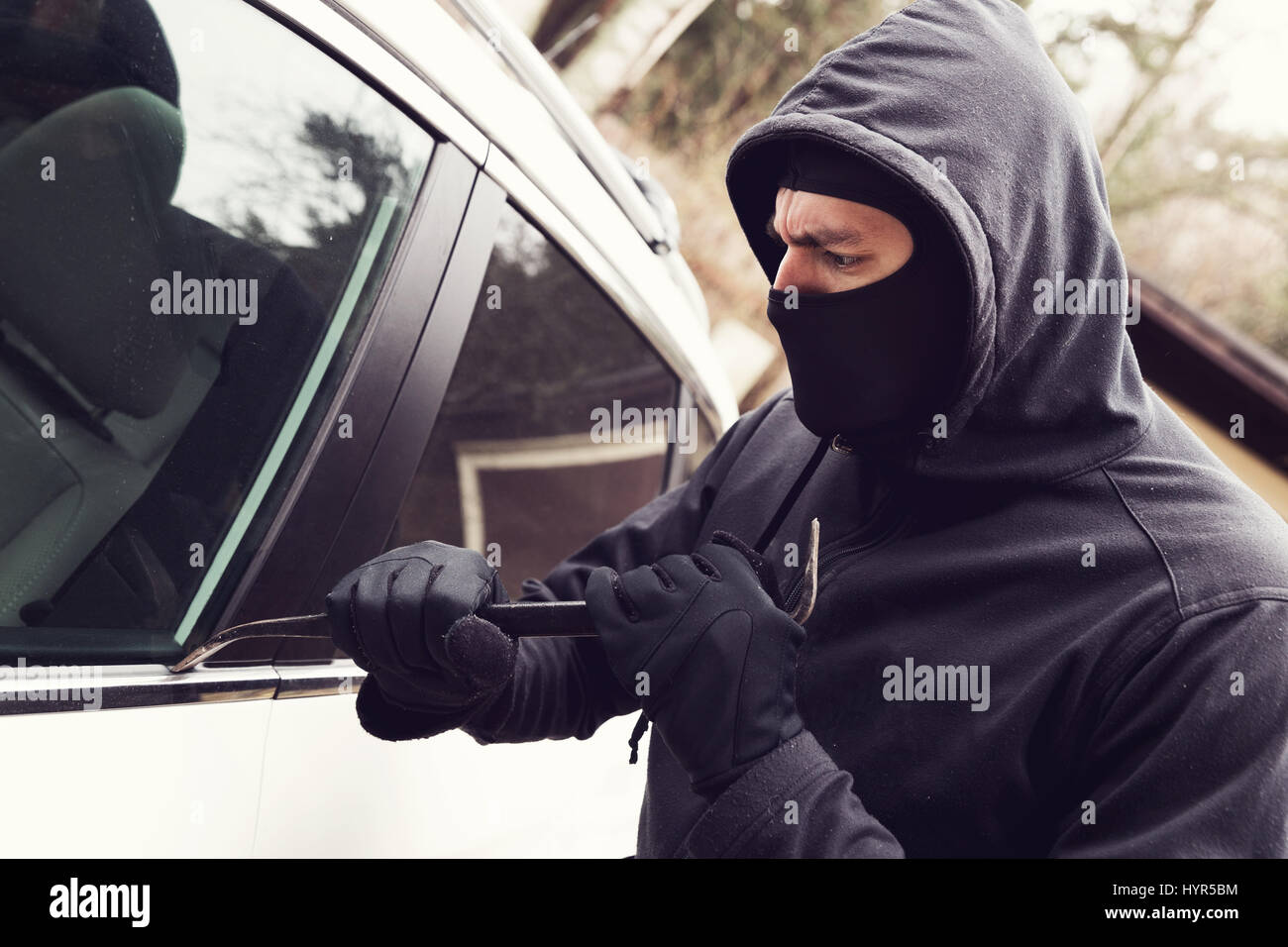 Los robos de coches - ladrón que intenta penetrar en el vehículo Foto de stock
