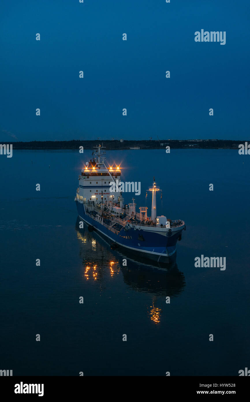 Buque de carga sale del puerto y navegando hacia el mar abierto, escena de crepúsculo Foto de stock