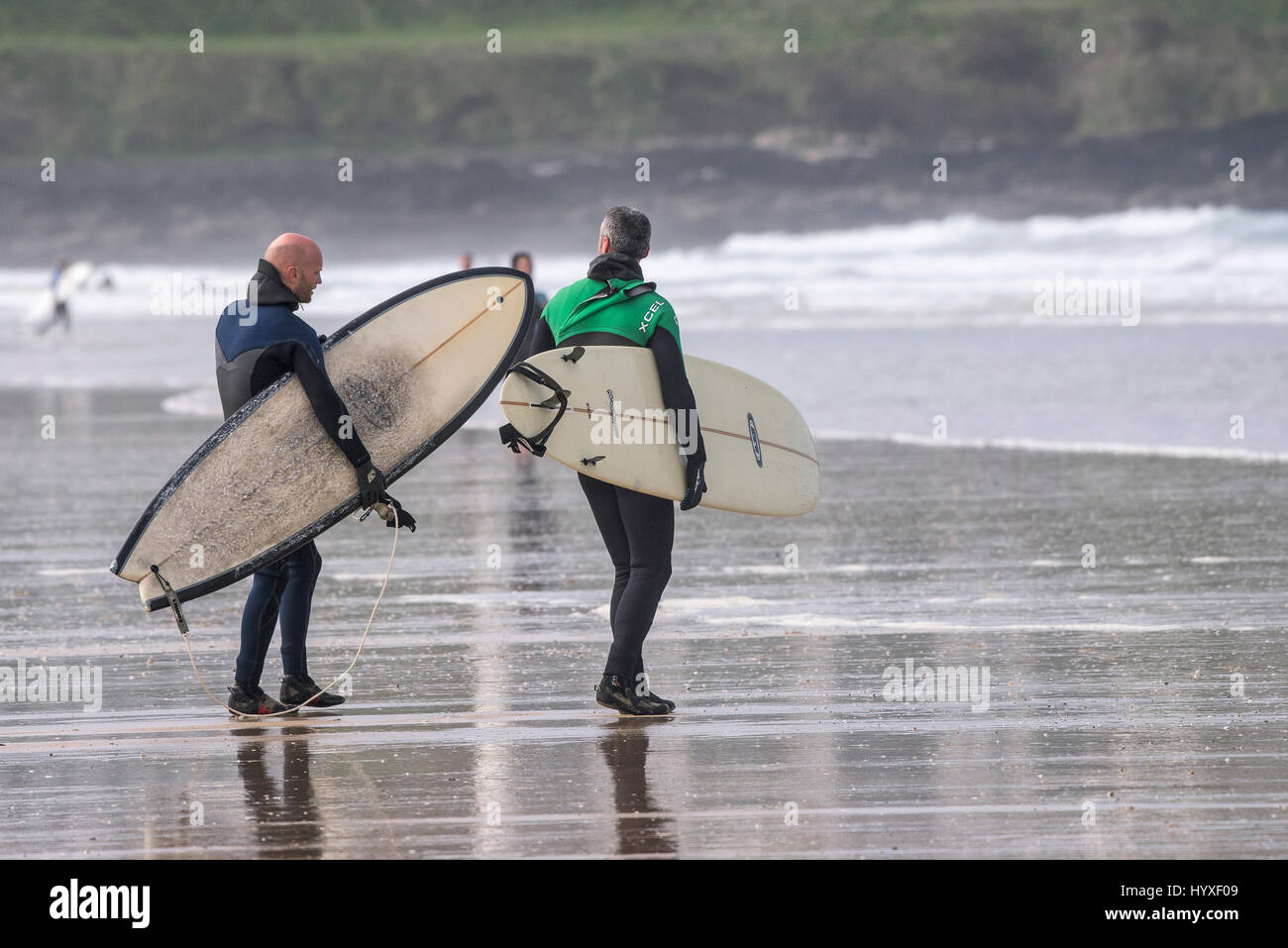 Dos surfistas llevar tablas de surf surf UK Cornwall caminando sobre náutica de recreo en el estilo de vida de actividad de ocio amigos Foto de stock