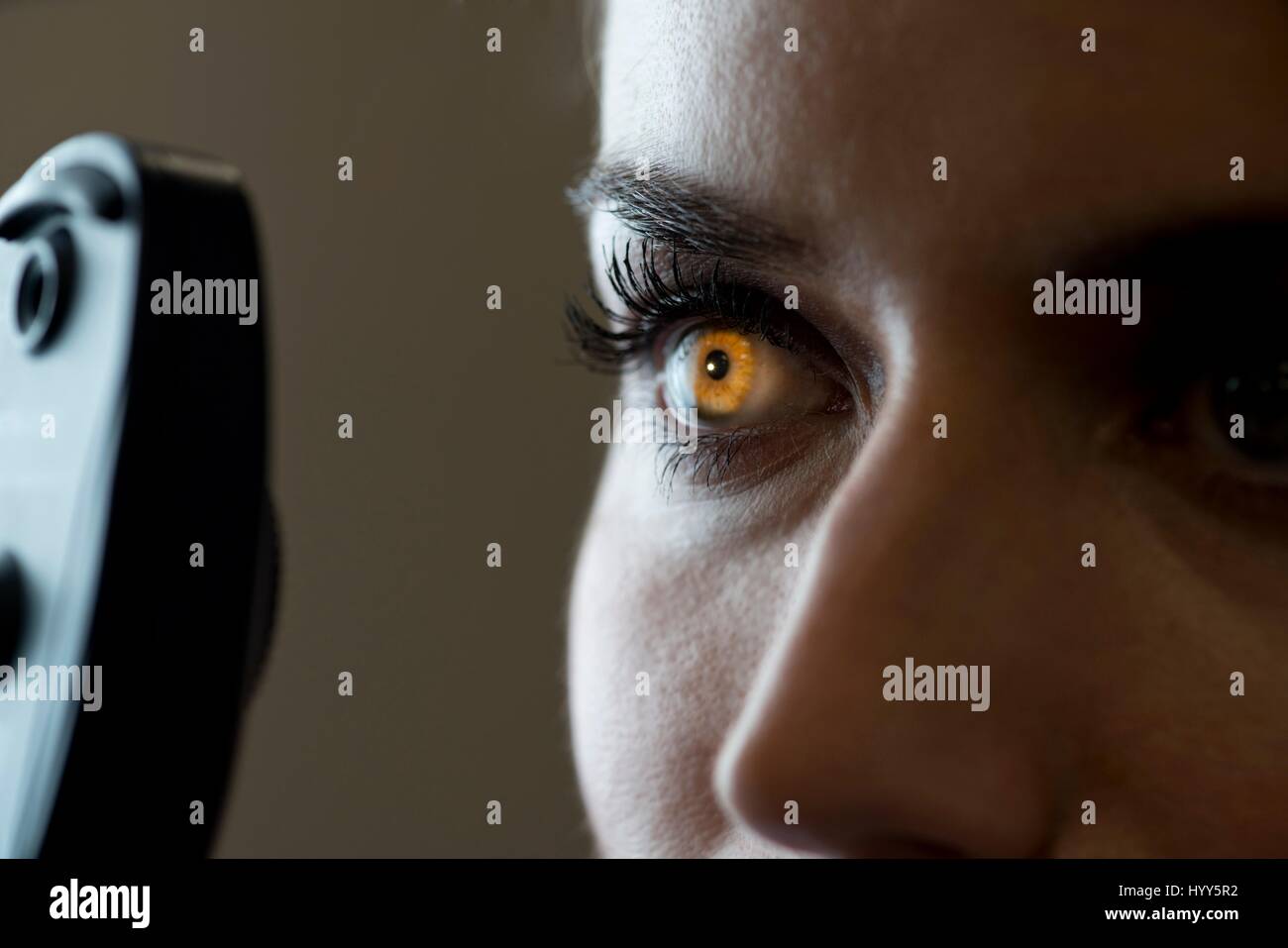 Mujer que prueba ocular con luz que brilla en el iris. Foto de stock