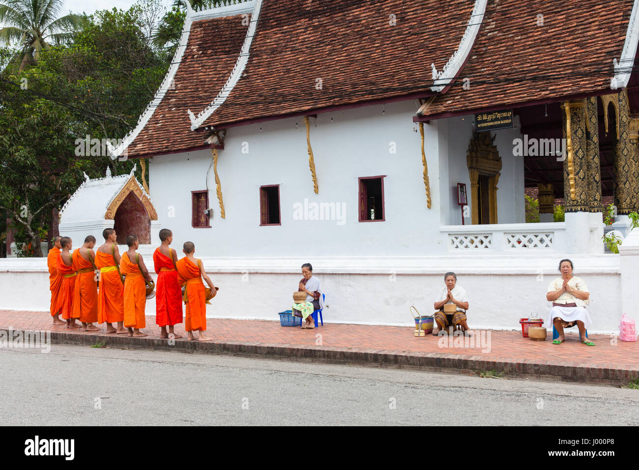 La República Democrática Popular Lao, Laos, Luang Prabang - 22 Junio 2014: Mujer ora después de dar limosna a los monjes budistas en la calle. Foto de stock