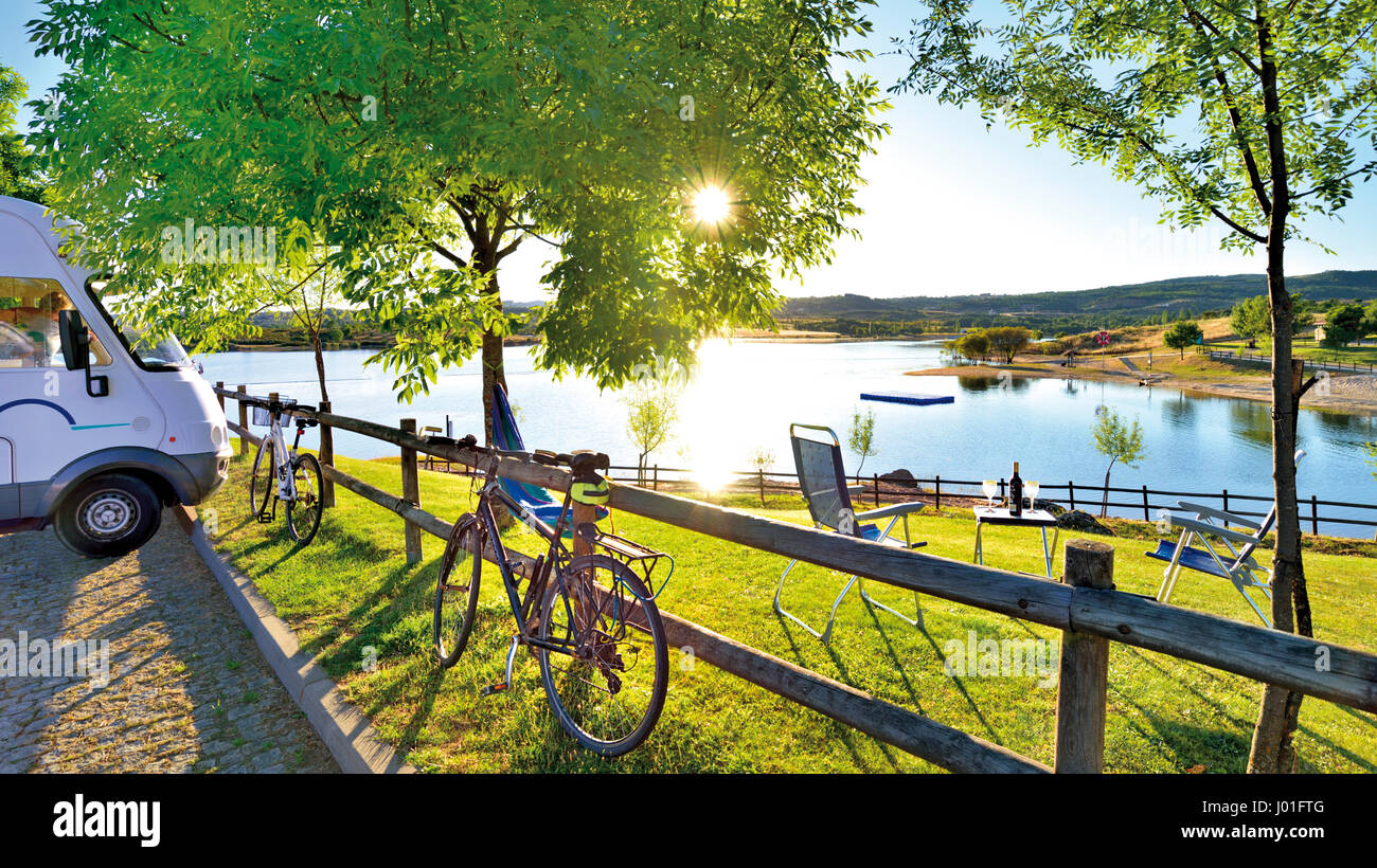 Motorhome y aparcamiento para bicicletas en el romántico punto chill-out con tumbonas, mesa de camping, vino y vistas al lago Foto de stock