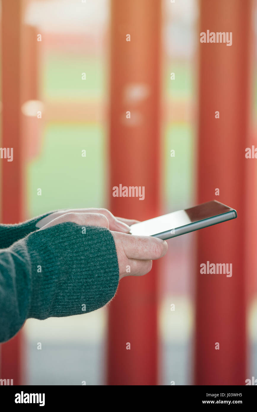 Cerca del auténtico manos femeninas en la calle a través de teléfono móvil para enviar un mensaje de texto Foto de stock