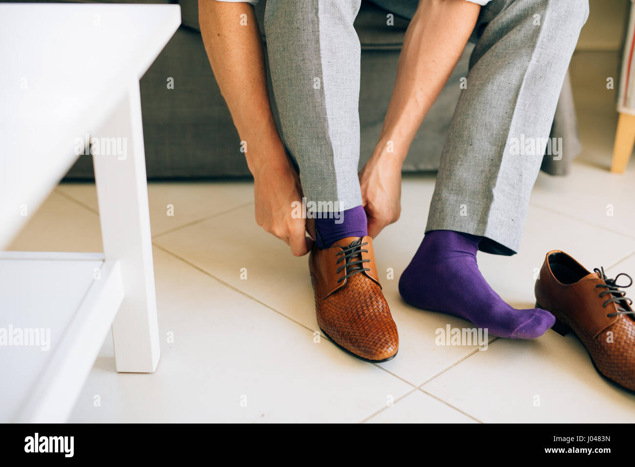 El hombre en gris, pantalones y un vestido de púrpura calcetines zapatos  con cordones marrón sentado en el sofá Fotografía de stock - Alamy