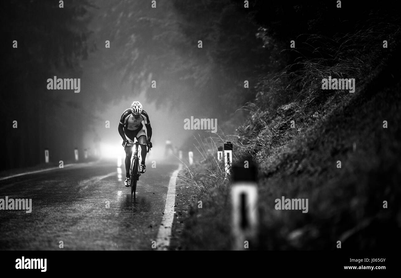 Un ciclista profesional carreras hasta la montaña Geisberg en niebla y lluvia en la bicicleta de carreras carrera Geisberg-Rennen cerca de Salzburgo, en 2015 Foto de stock