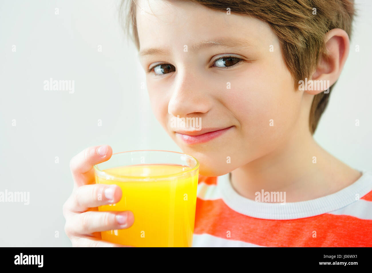 Chico sonriente disfrutando con un vaso de jugo amarillo Foto de stock