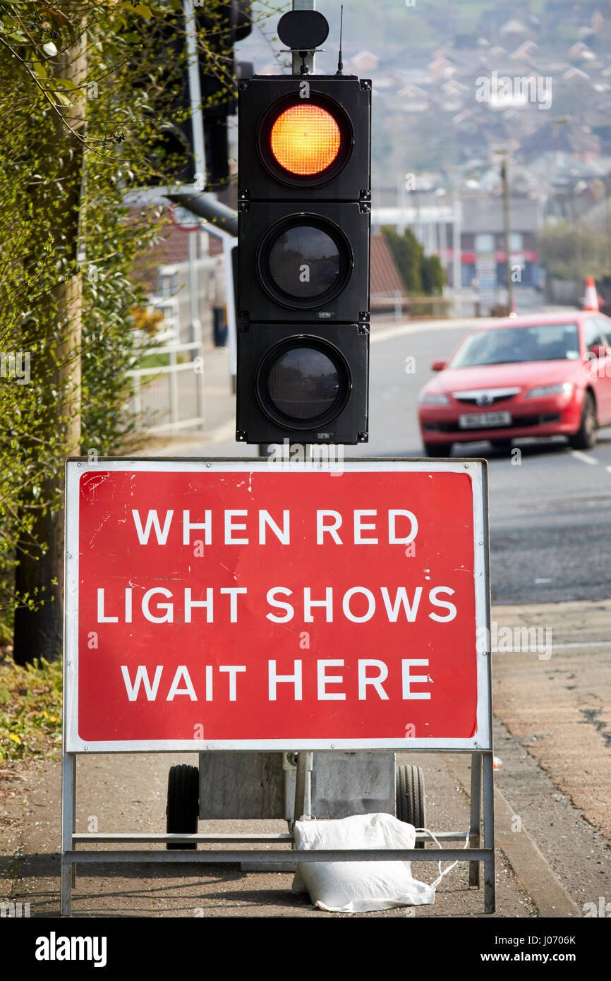 Cuando la luz roja muestra espera aquí firmar bajo temporal de semáforos en reparaciones viales Newtownabbey UK Foto de stock
