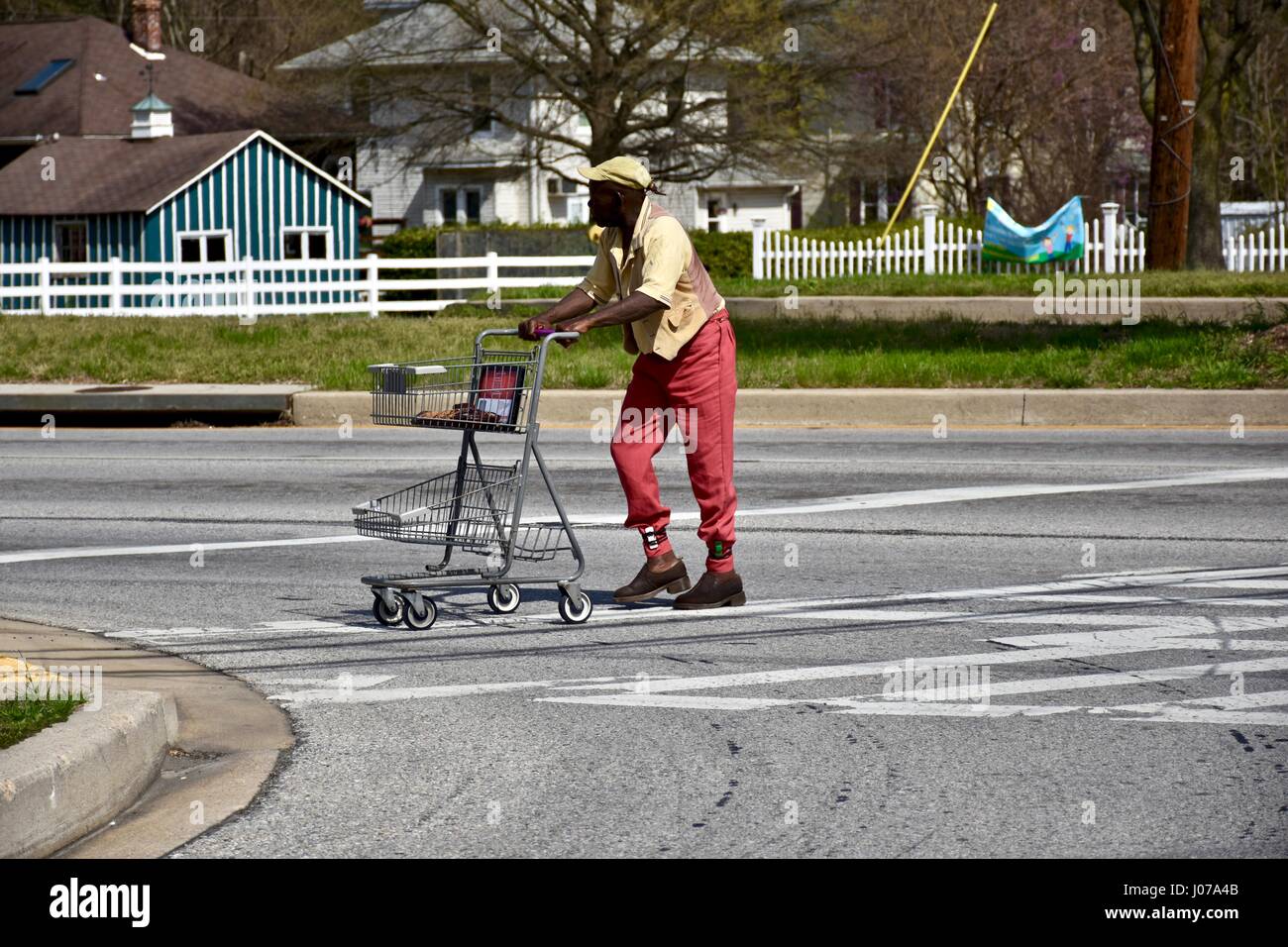 Hombre Negro empujando el canasto cruzando la calle Foto de stock
