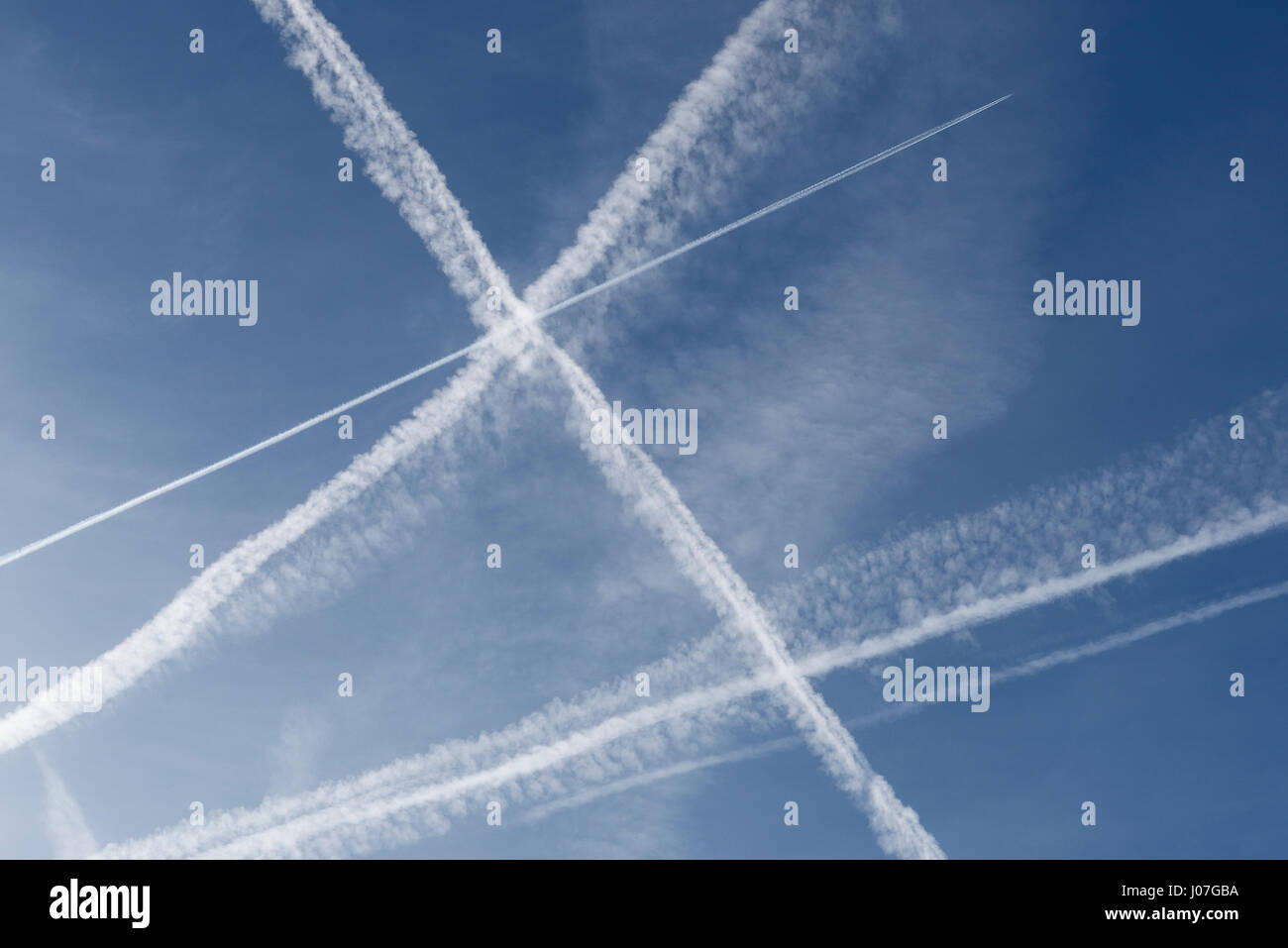 Los vapores de avión senderos a través de un cielo azul profundo Foto de stock