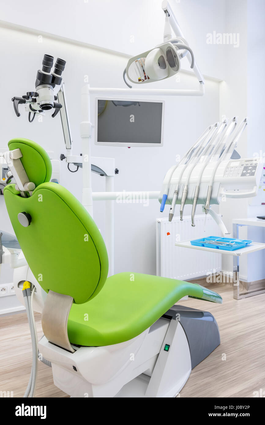 Clínica dental profesional con interiores modernos, sillón verde,  microscopio, lámpara LED y pantalla Fotografía de stock - Alamy