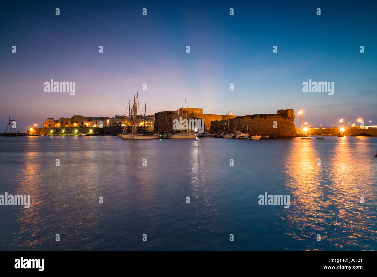 Crepúsculo ilumina el puerto y el casco antiguo medieval de Gallipoli, Provincia de Lecce, Puglia, Italia Foto de stock