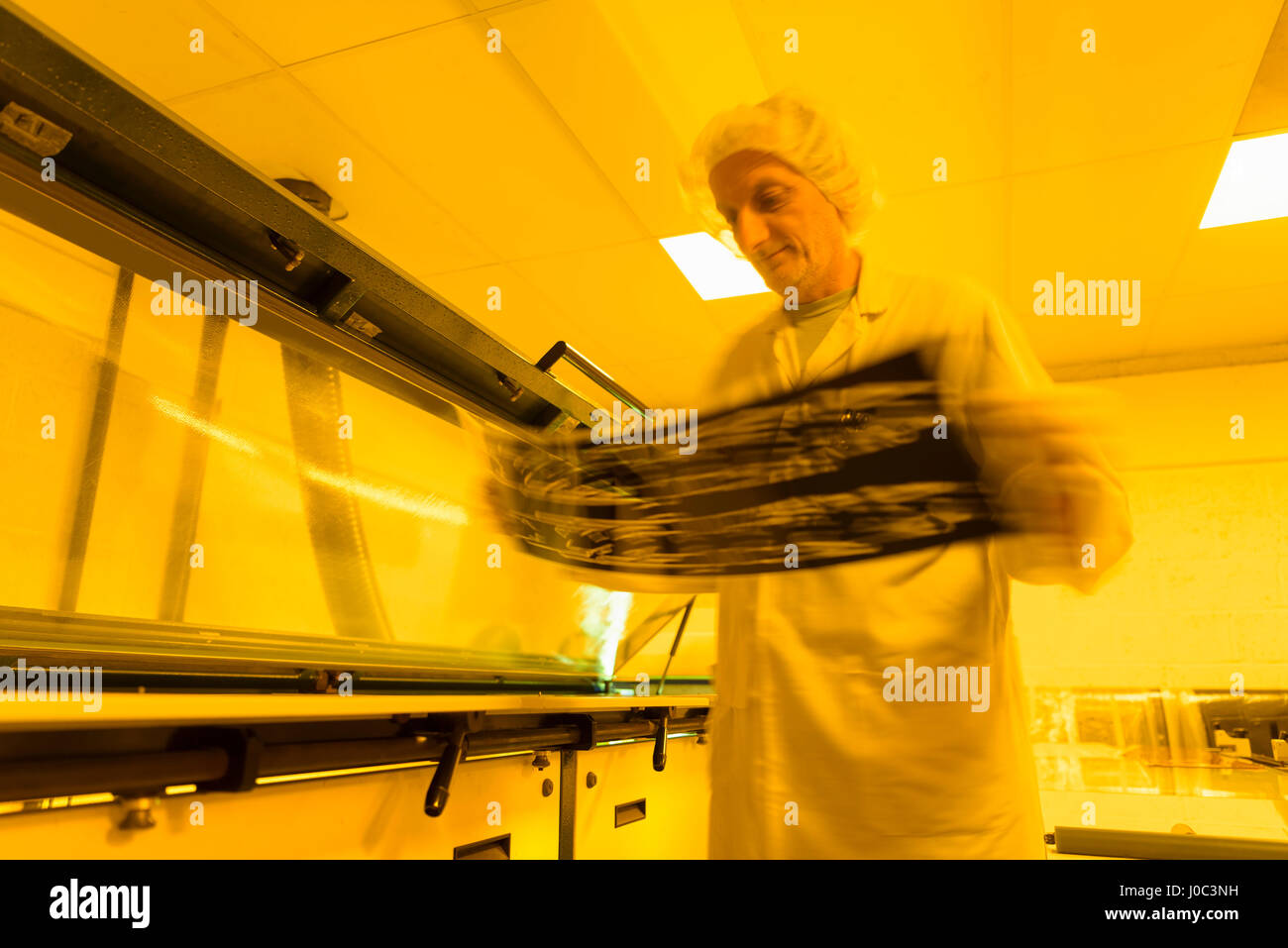 Inspección trabajador negativo de placa de circuito en caja de luz amarilla en electrónica fábrica Foto de stock