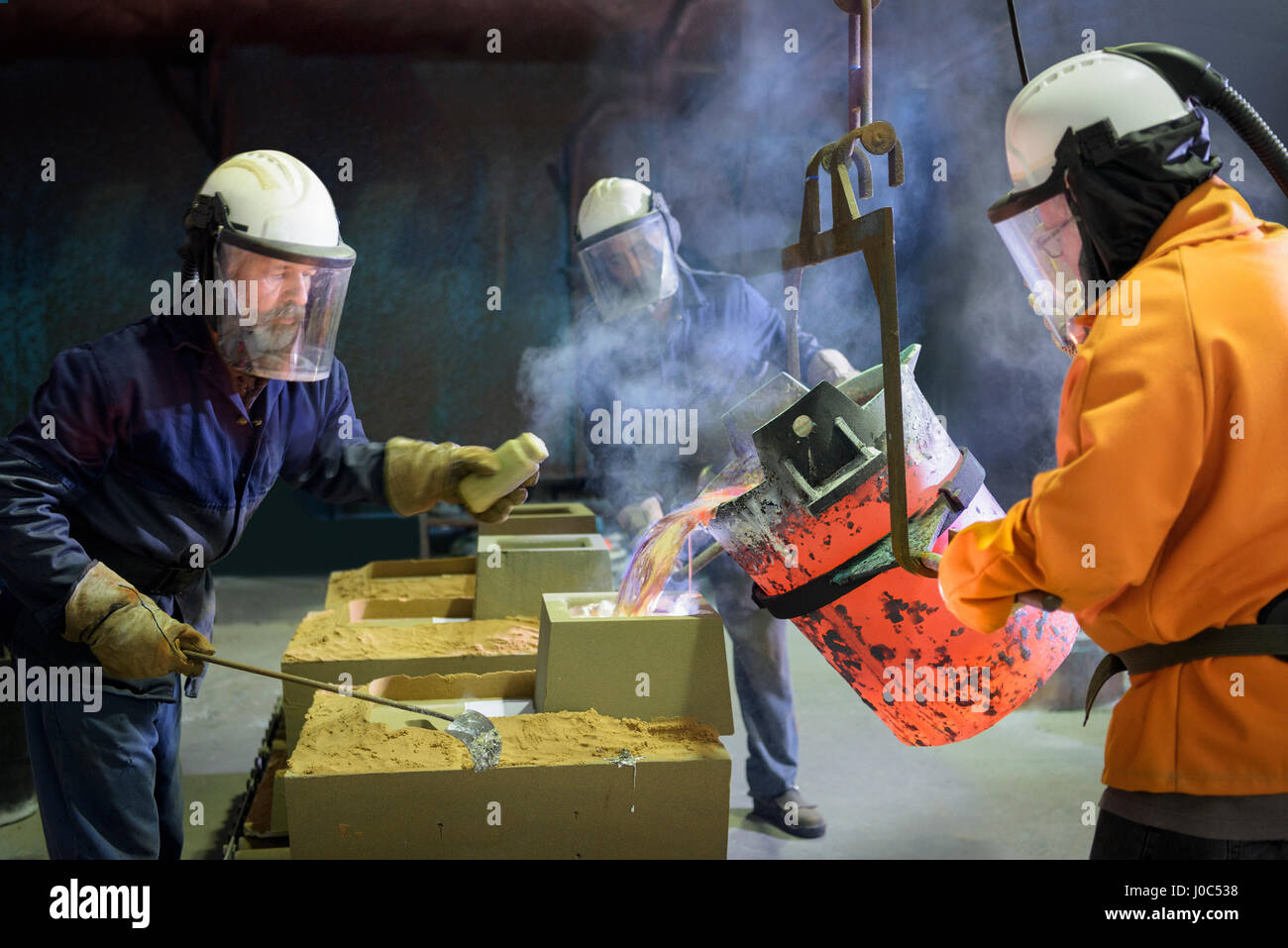 Los trabajadores de aleación de aluminio fundido vertido en el molde en la fábrica de fundición de precisión Foto de stock