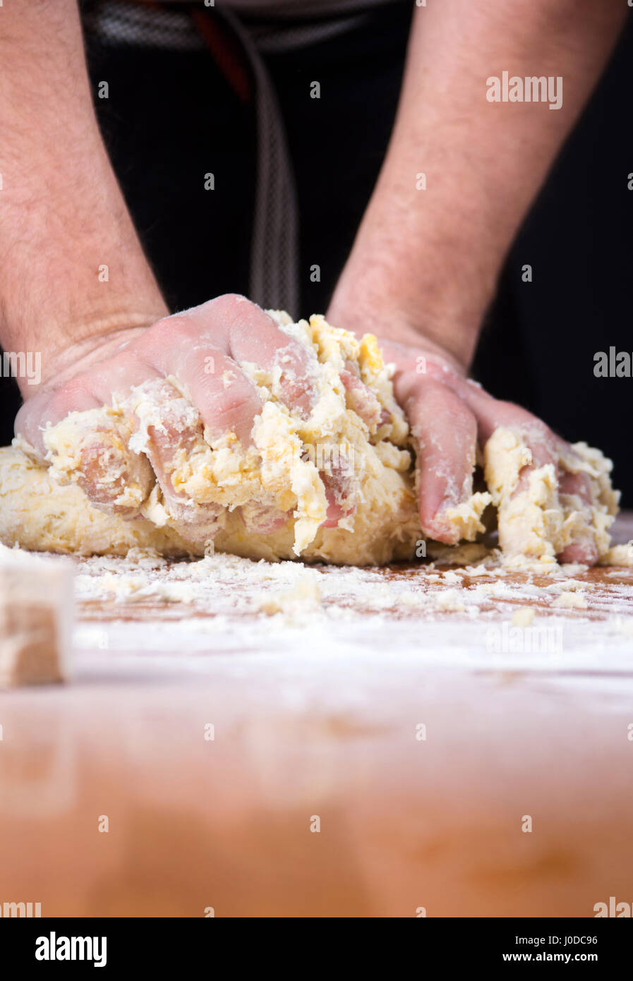 Baker macho amasar la masa sobre una mesa recubierta de harina Foto de stock