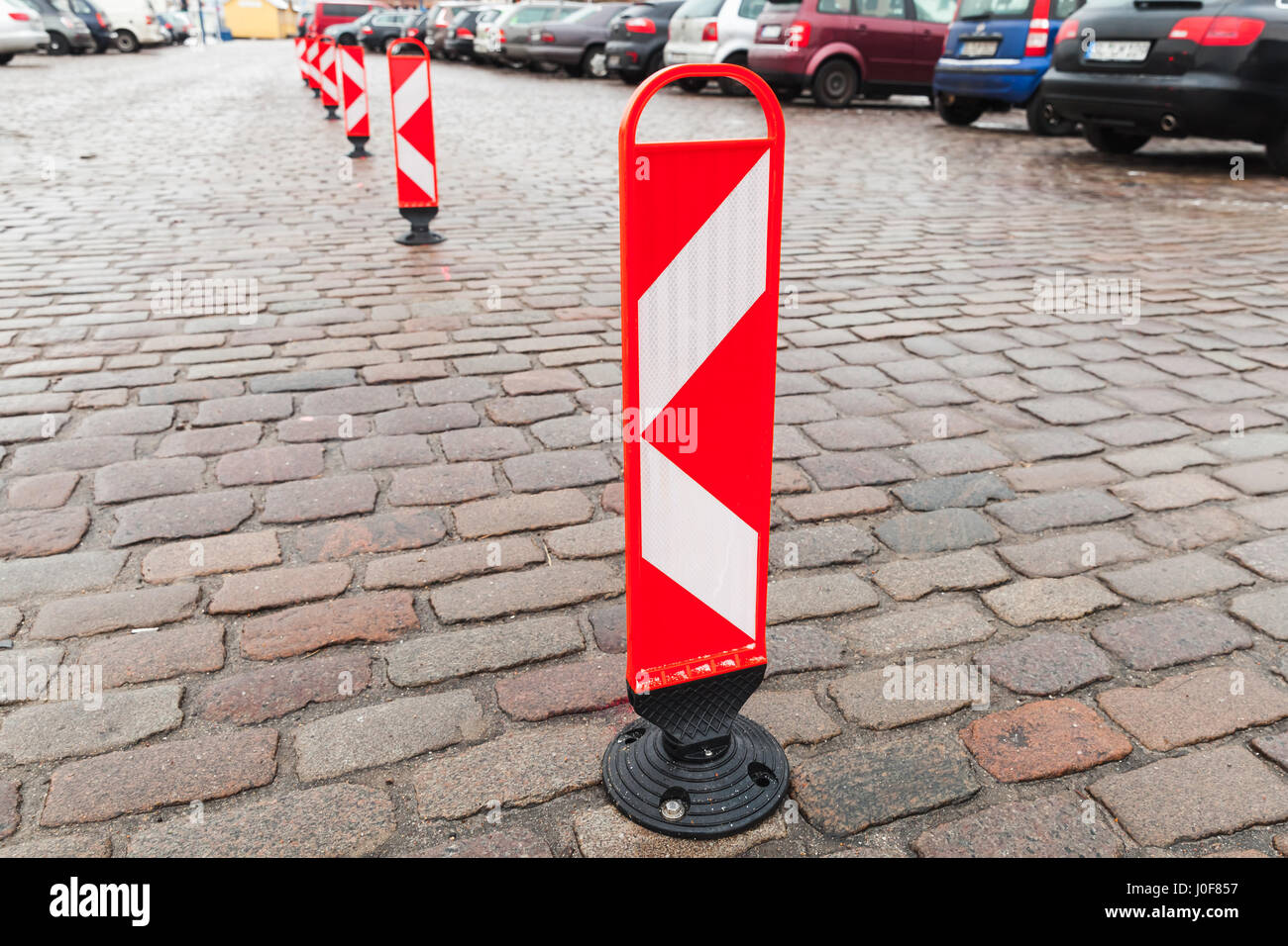 Rayas blancas y rojas verticales señales de precaución de pie en una fila para dividir una zona de estacionamiento Foto de stock