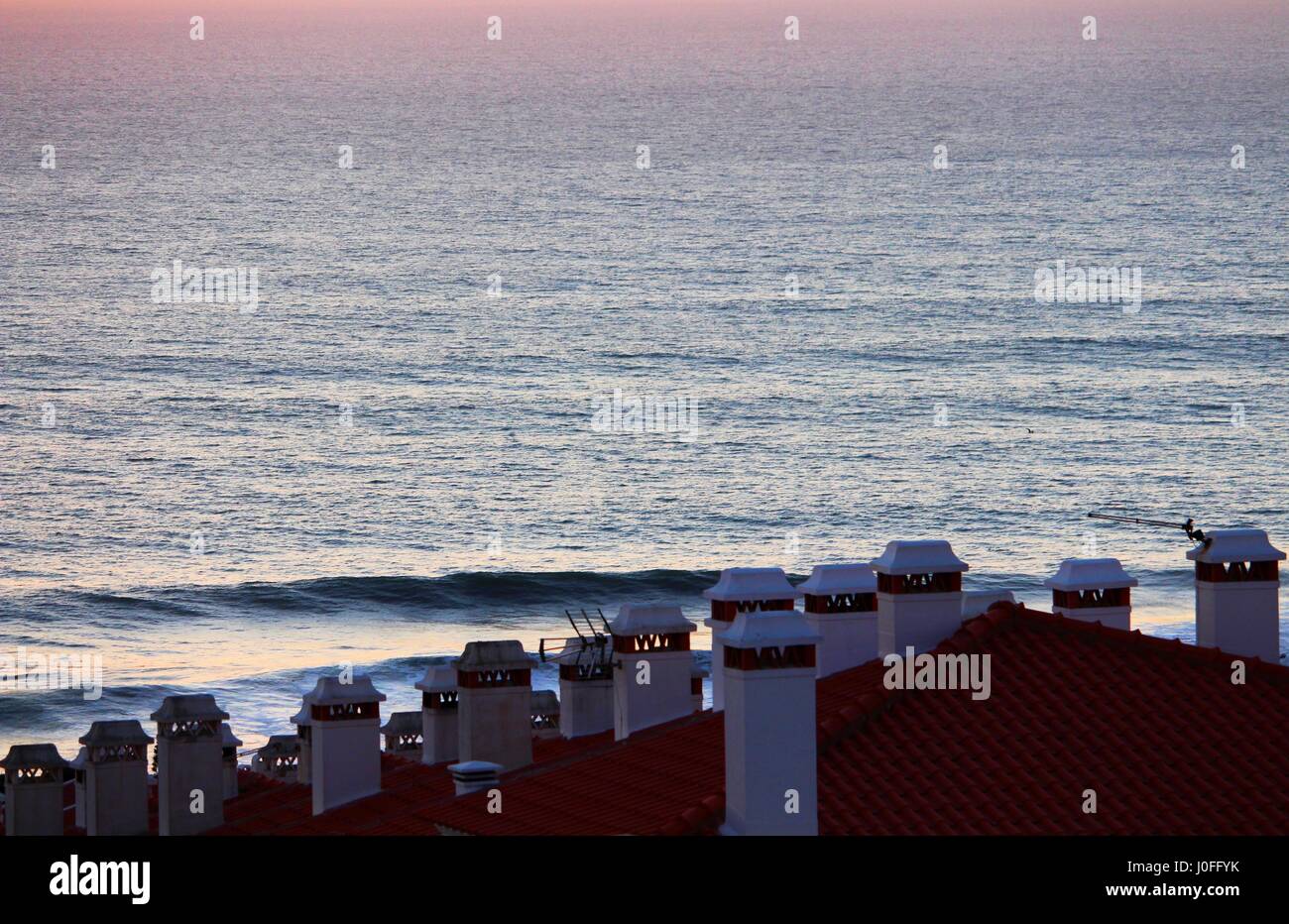 Los tejados de algunas casas en Ericeira, Portugal, con vistas al mar. Foto de stock