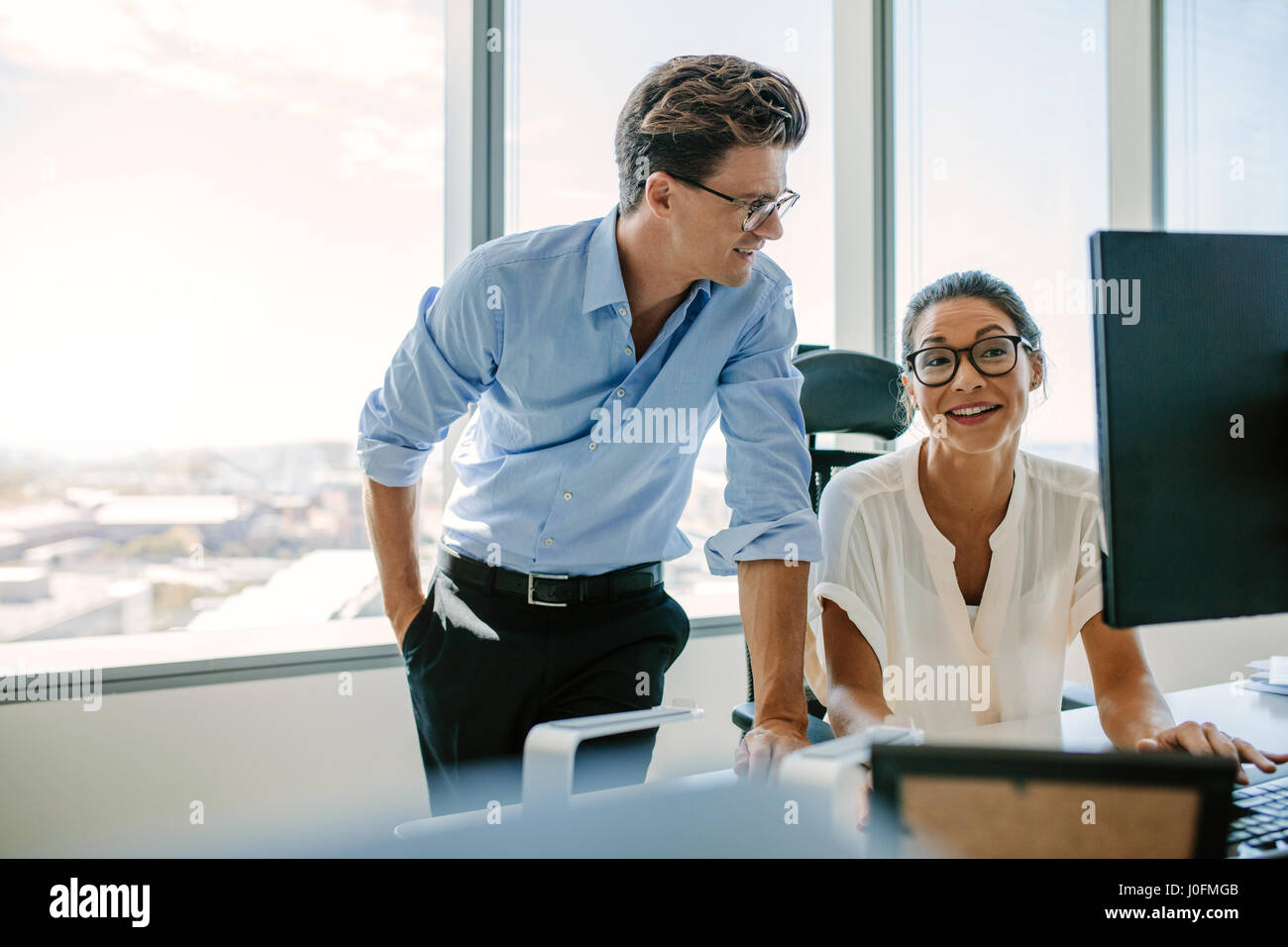 Feliz colegas de negocios trabajando juntos en su mesa. Mujer asiática con el colega masculino en la oficina moderna. Foto de stock