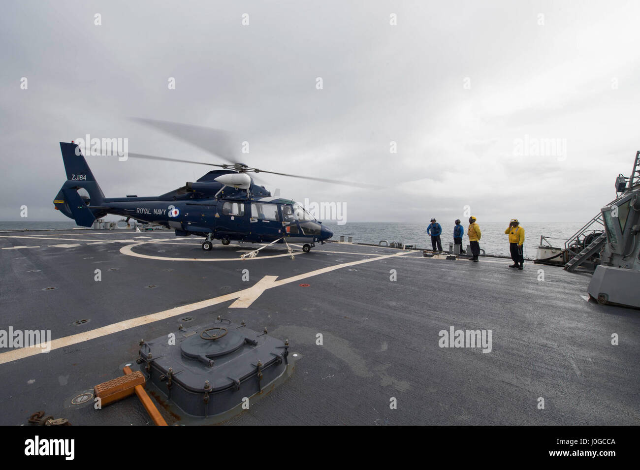 170331-N-ZE250-181 OCÉANO ATLÁNTICO - (Marzo 31, 2017) - El Royal Navy helicóptero Dauphin HH-65 se prepara para realizar una transferencia de personal a bordo del USS Carney (DDG 64) durante el ejercicio Joint Warrior 17-1 del 31 de marzo de 2017. Carney, un Arleigh Burke clase destructor de misiles guiados, desplegadas a Rota, España, está realizando su tercera patrulla en los EE.UU. 6ª Flota de la zona de operaciones en apoyo de los intereses de seguridad nacional de EE.UU. en Europa. (Ee.Uu. Navy photo by Mass Communication Specialist 3ª clase Weston Jones/liberado) Foto de stock