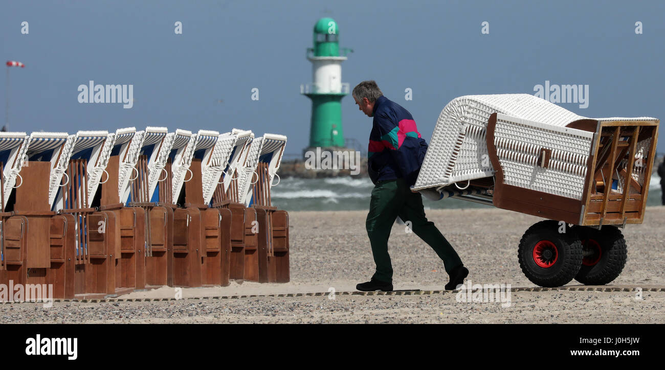 Warnemuende (Alemania). 13 abr, 2017. Un hombre pone alquilables pueden alquilar sillas de playa para el fin de semana de Semana Santa en la ciudad de Mar Báltico Warnemuende (Alemania), 13 de abril de 2017. Según el Servicio Meteorológico Alemán (DWD), el clima seguirá siendo caprichoso y frío en este año de la Semana Santa. Foto: Bernd Wüstneck/dpa-Zentralbild/dpa/Alamy Live News Foto de stock