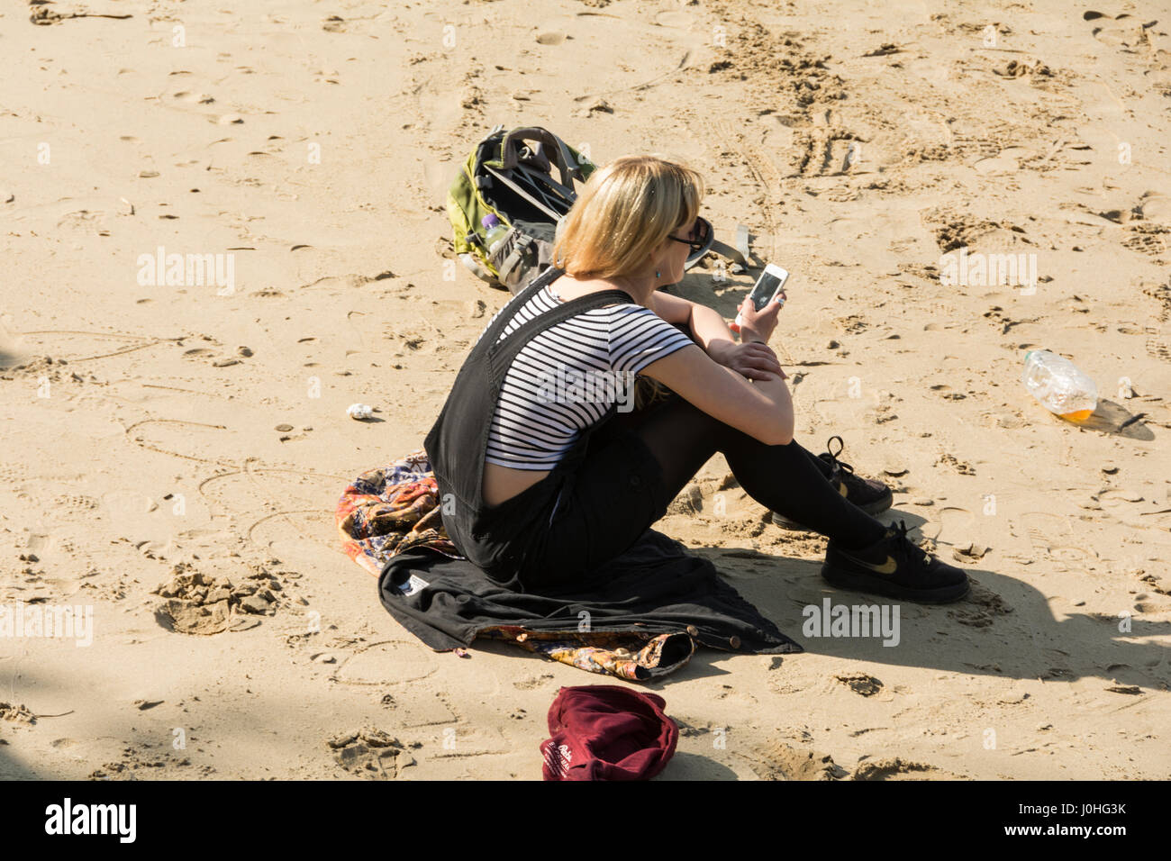 Una solitaria mujer sentada sola en la playa al lado del río Támesis, cerca de South Bank de Londres. Foto de stock