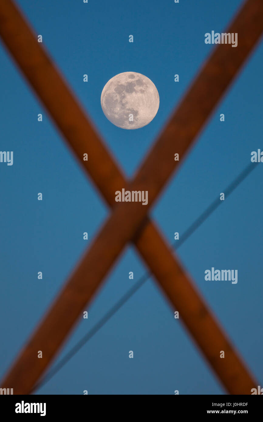Luna en el medio de x forma poste eléctrico de madera Foto de stock