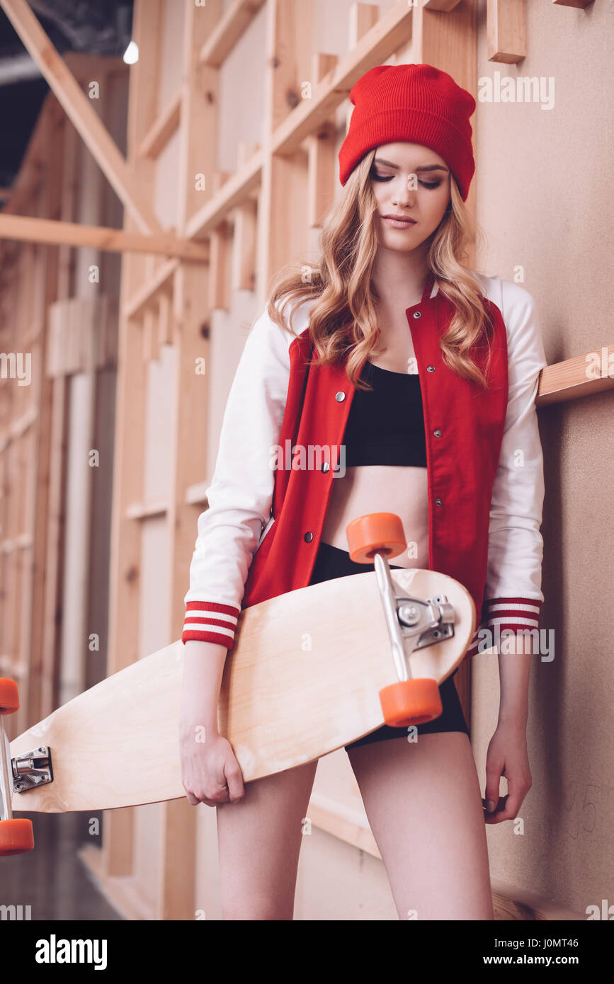 Estilo hipster mujer en béisbol chaqueta con longboard posando en pared de  madera Fotografía de stock - Alamy