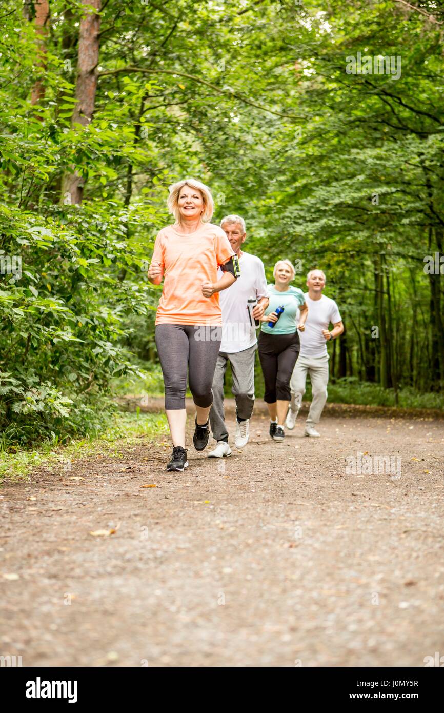 Cuatro personas corriendo en la pista en los bosques. Foto de stock