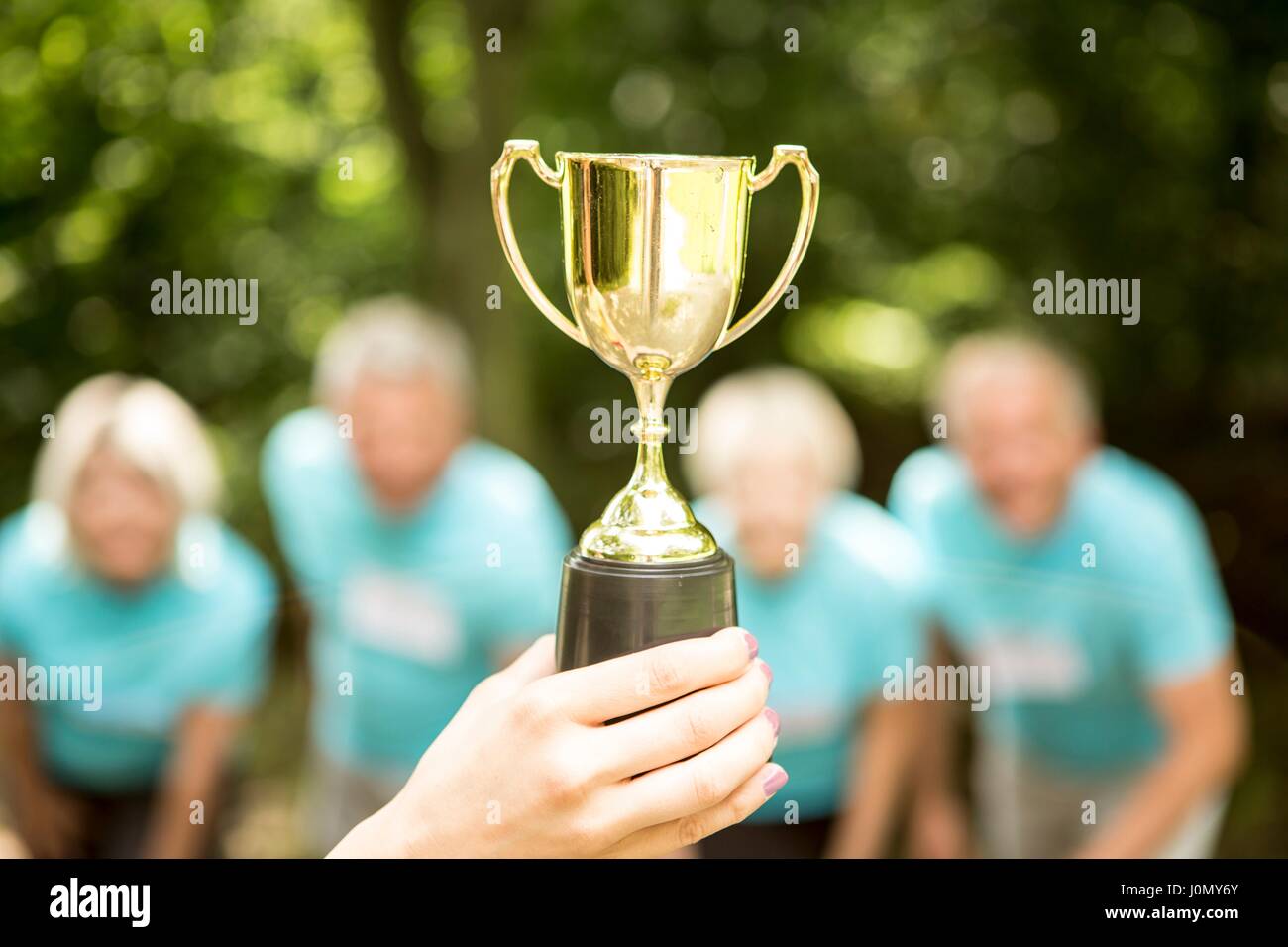 Persona sosteniendo el trofeo con la gente en el fondo. Foto de stock