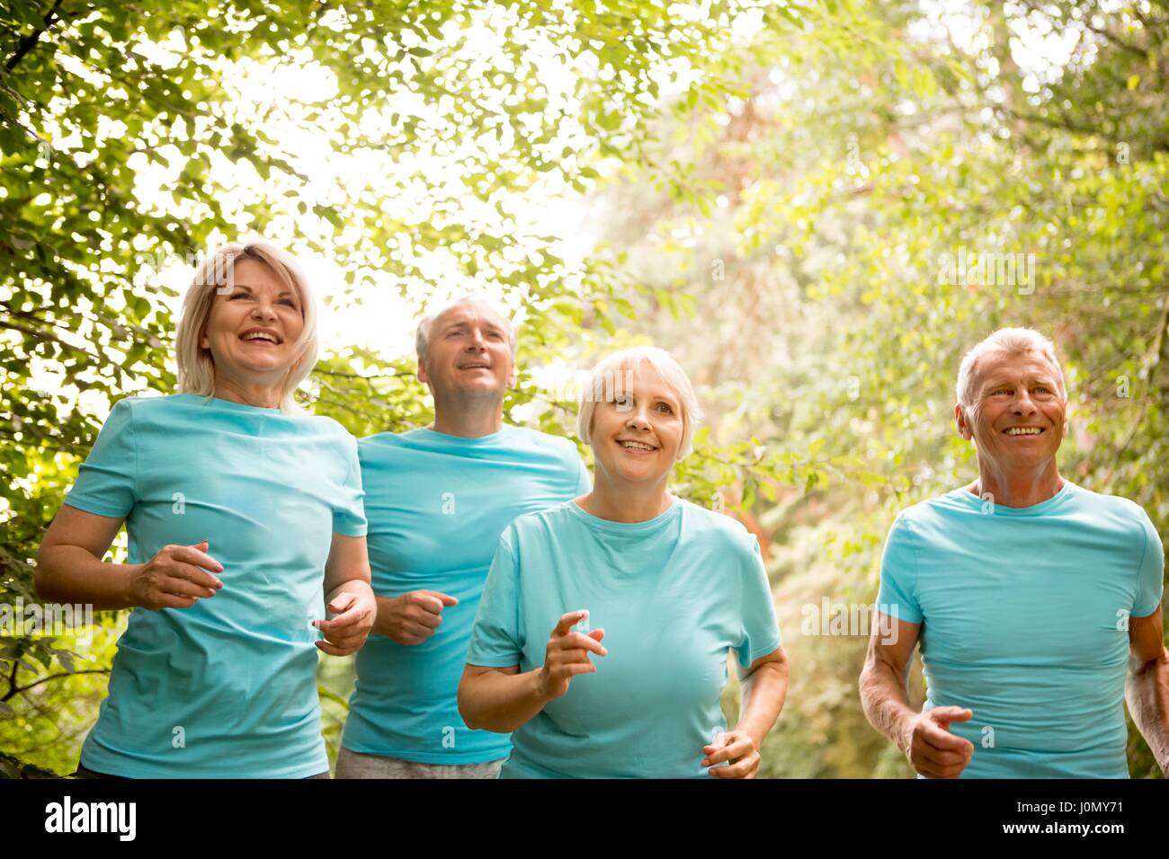 Cuatro personas corriendo en una carrera, sonriendo. Foto de stock