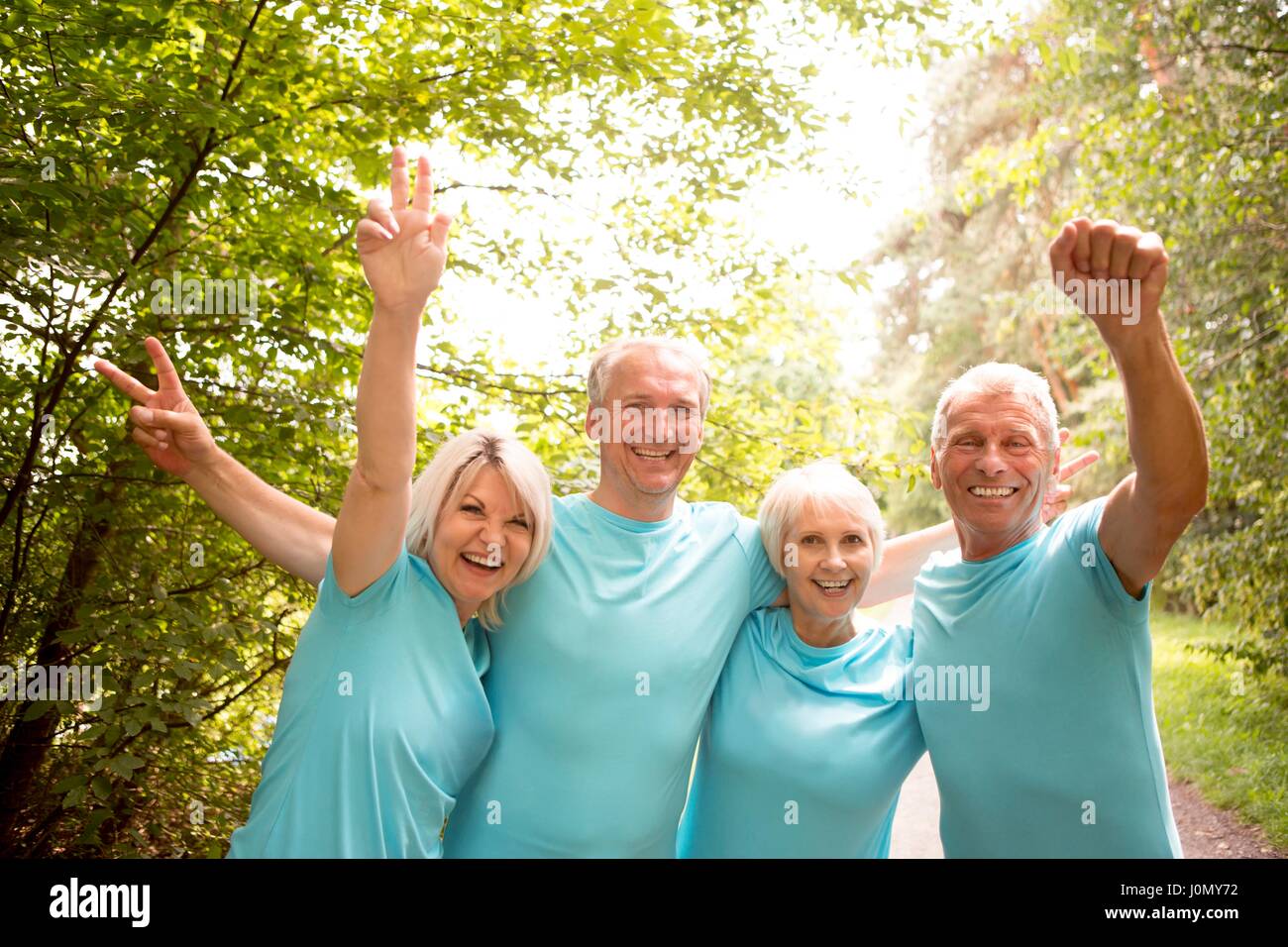 Cuatro personas en azul t-shirts, sonriente y aplaudiendo. Foto de stock