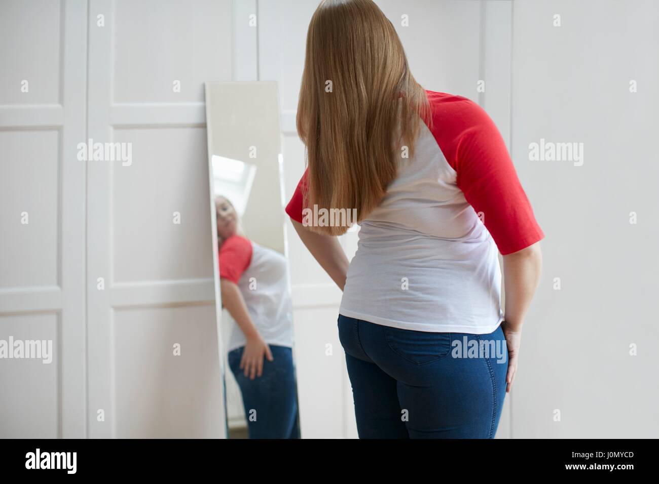 Mujer joven busca en el reflejo en el espejo. Foto de stock