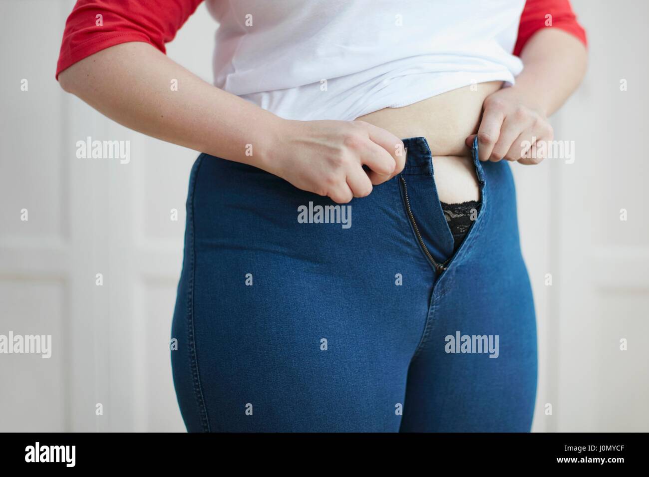 Mujer tratando al botón jeans más barriga. Foto de stock