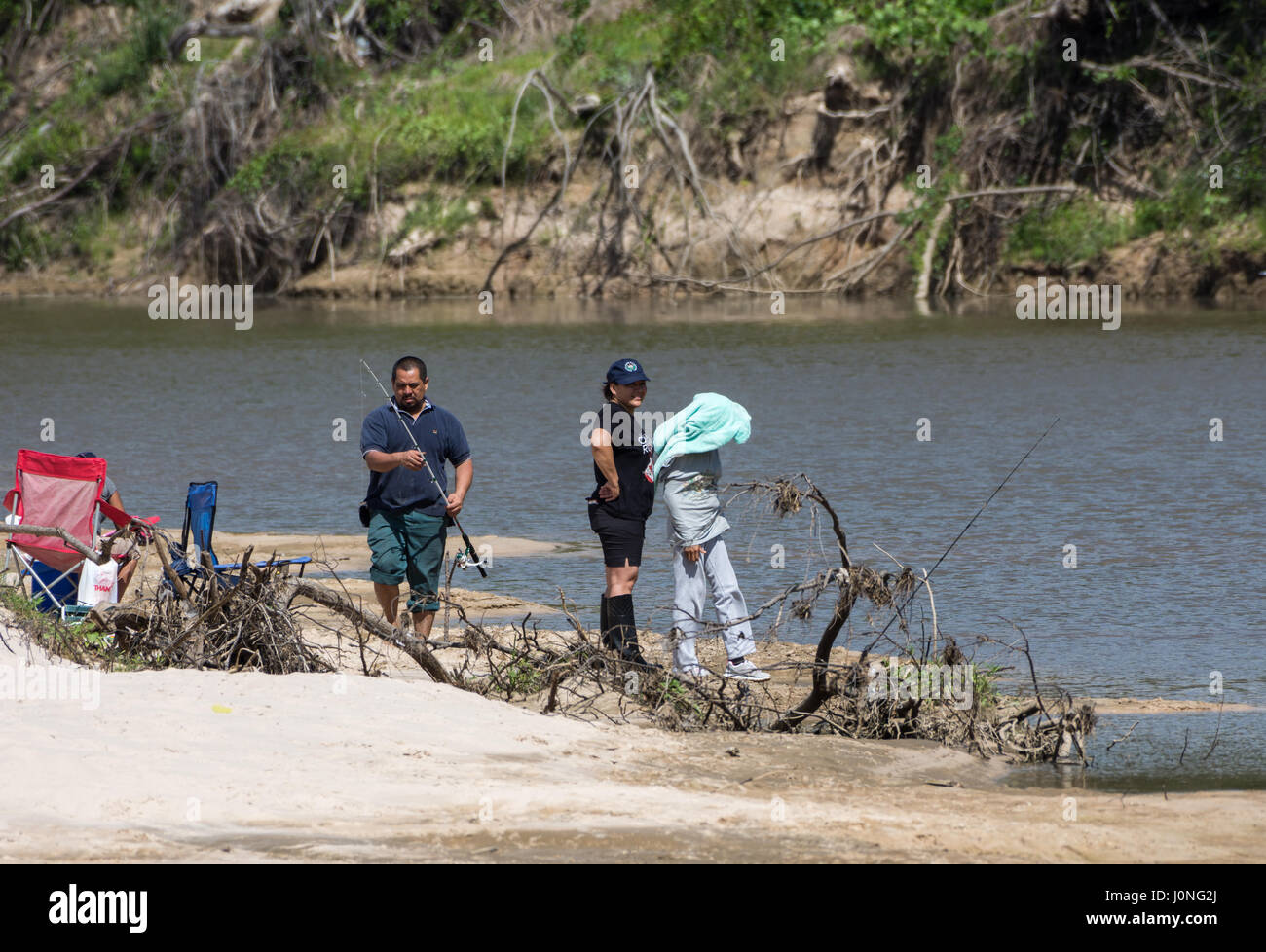 Una familia hispana pesca por un río. Texas, EE.UU. Foto de stock