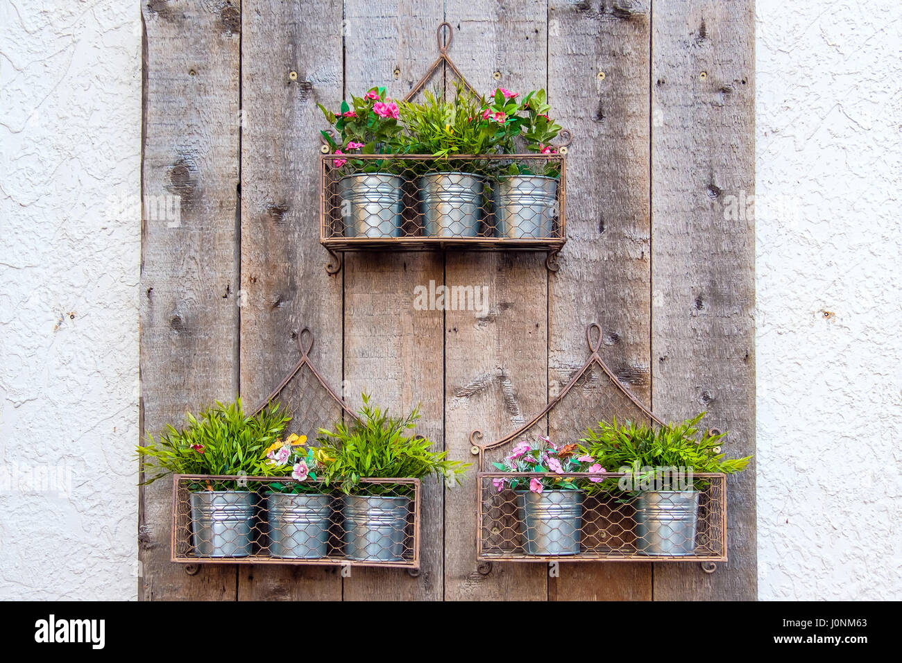 Flores en macetas colgantes metálicos instalados en la pared Fotografía de  stock - Alamy