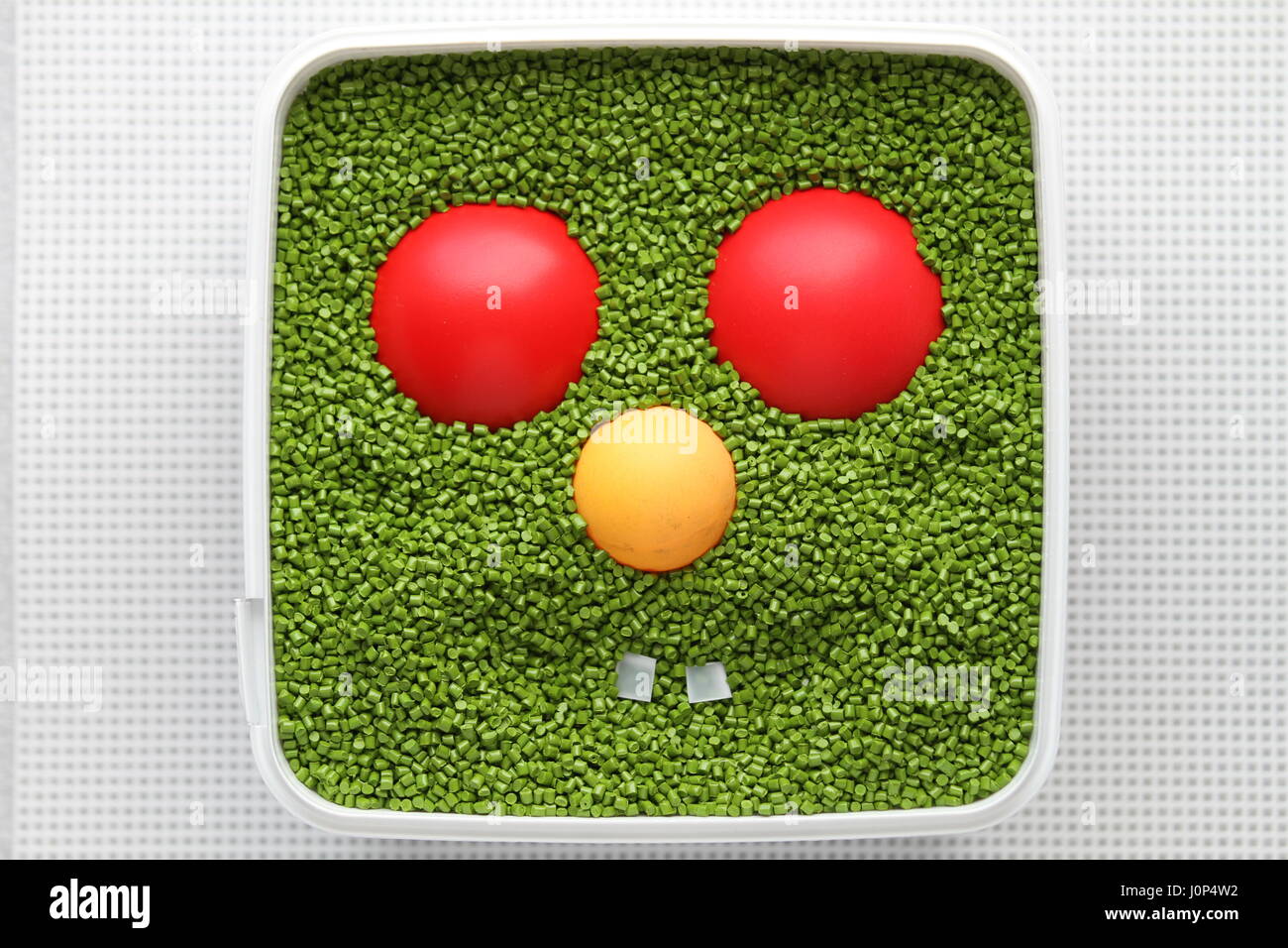 Emoticon verde con ojos rojos, nariz amarilla sobre un fondo blanco. Para el uso de emoticonos en los juegos de ordenador y diseño web. Diseño creativo. Sonrisa. Plástico. Foto de stock