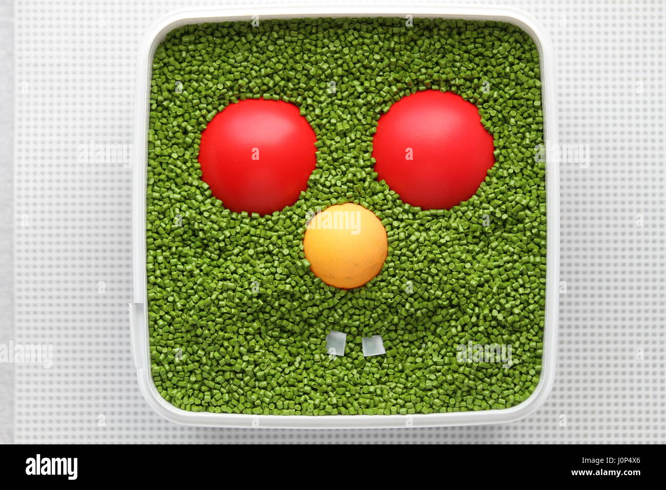 Emoticon verde con ojos rojos, nariz amarilla sobre un fondo blanco. Para el uso de emoticonos en los juegos de ordenador y diseño web. Diseño creativo. Sonrisa. Plástico. Foto de stock