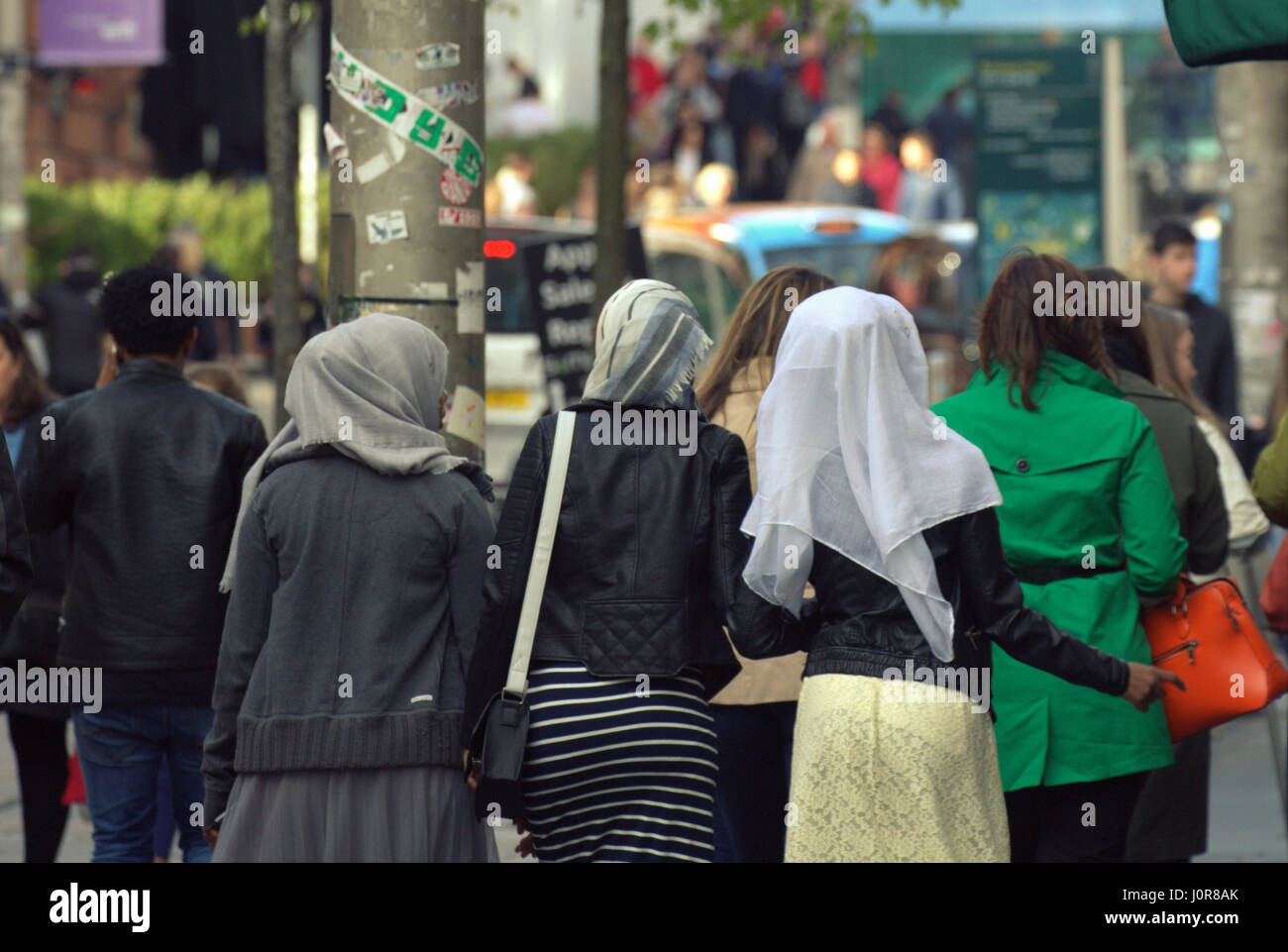 Los refugiados africanos asiáticos visten el Hijab pañuelo sobre calle escena cotidiana en el Reino Unido tres niñas caminando en multitud Foto de stock