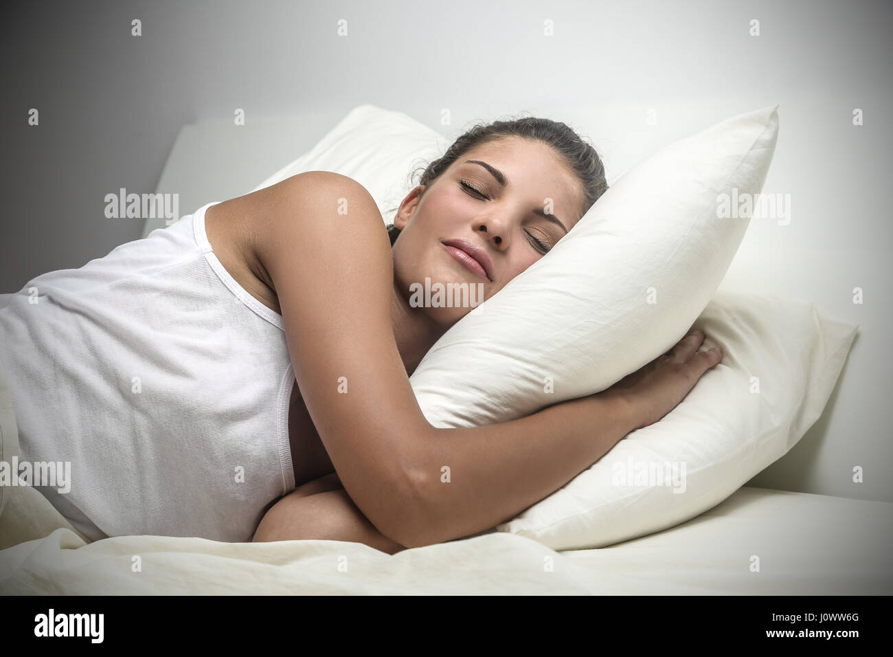 Mujer morena durmiendo en cama y abrazando la almohada Fotografía de stock  - Alamy