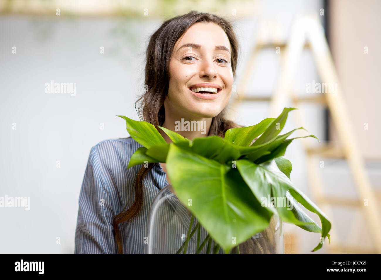 Mujer con planta en casa Foto de stock