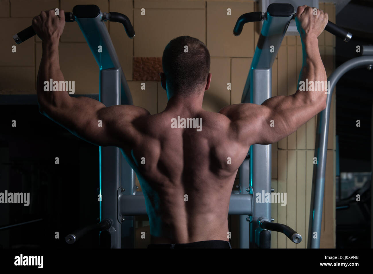 Hombre deportista haciendo tirar ups - Chin-Ups en el gimnasio. Foto de stock