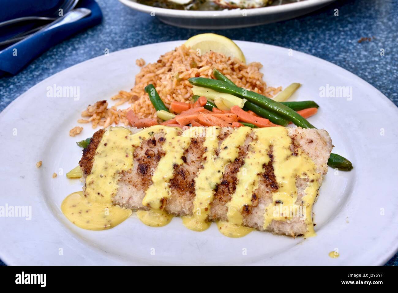 Mahi Mahi a la parrilla aderezada con salsa cremosa de lado servido con arroz y vegetales mixtos
