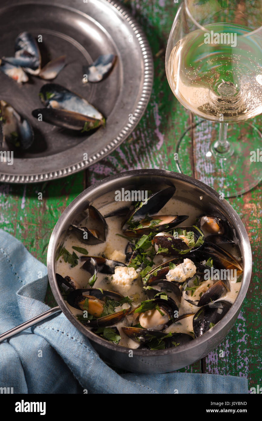 Mejillones en hojas en salsa sobre una chapa de estaño y en una cacerola Foto de stock