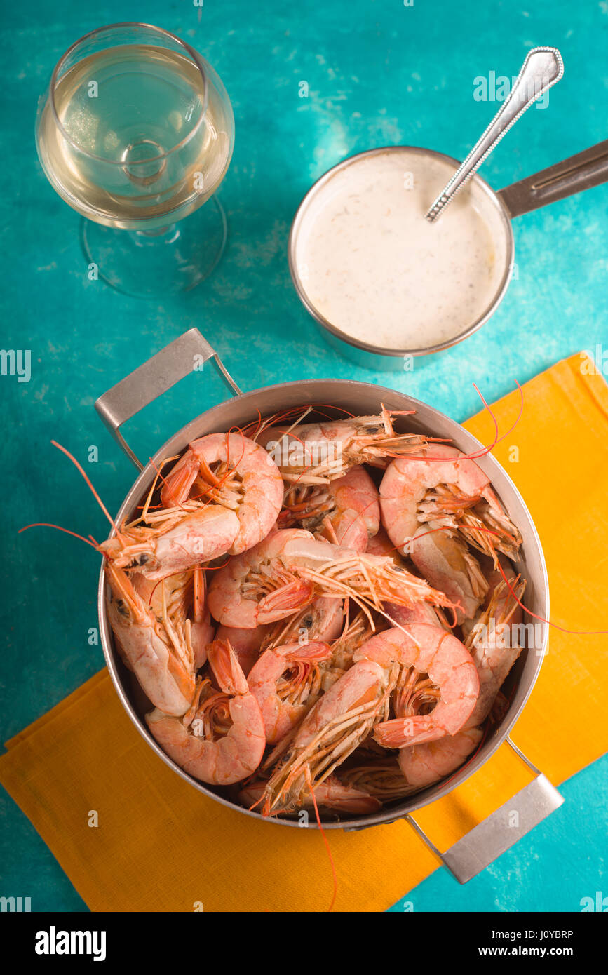 Camarones en una servilleta amarilla, cristal con vino blanco y salsa Foto de stock