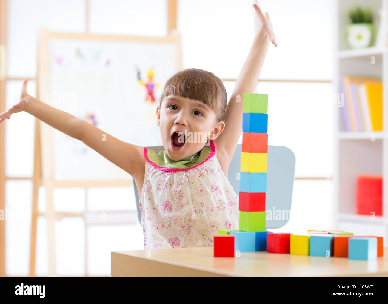 Niño feliz jugando con un bloque de juguetes en el centro de cuidado diurno Foto de stock