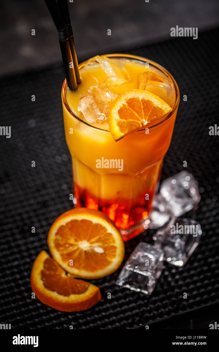 Licor de mango con jugo de naranja servido con rodajas de naranja, Ice Cube y paja Foto de stock